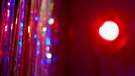 Shot-Of-Defocused-Tinsel-Curtain-And-Spotlight-In-Night-Club-Or-Disco-With-Reflected-Sparkling-Lights